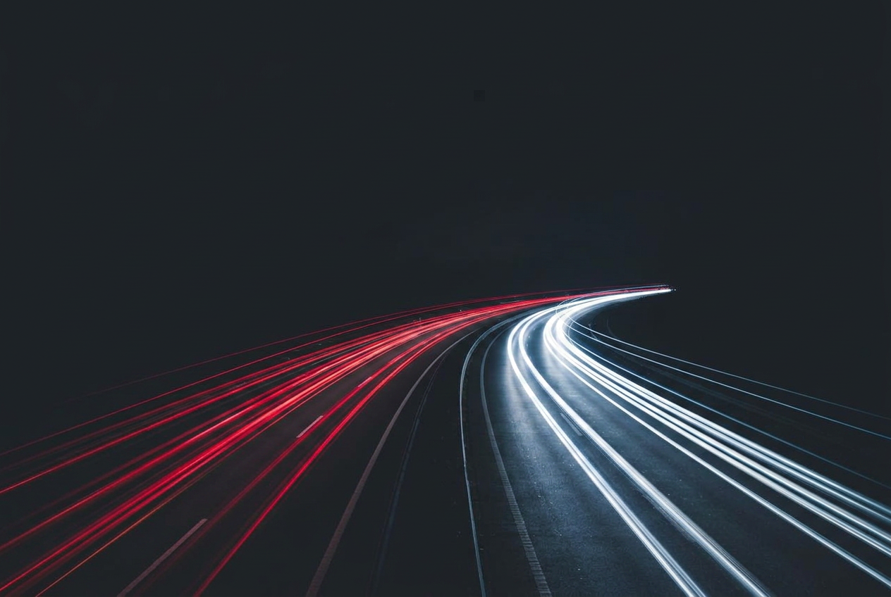 Red and white vehicle light trails along a dark night highway